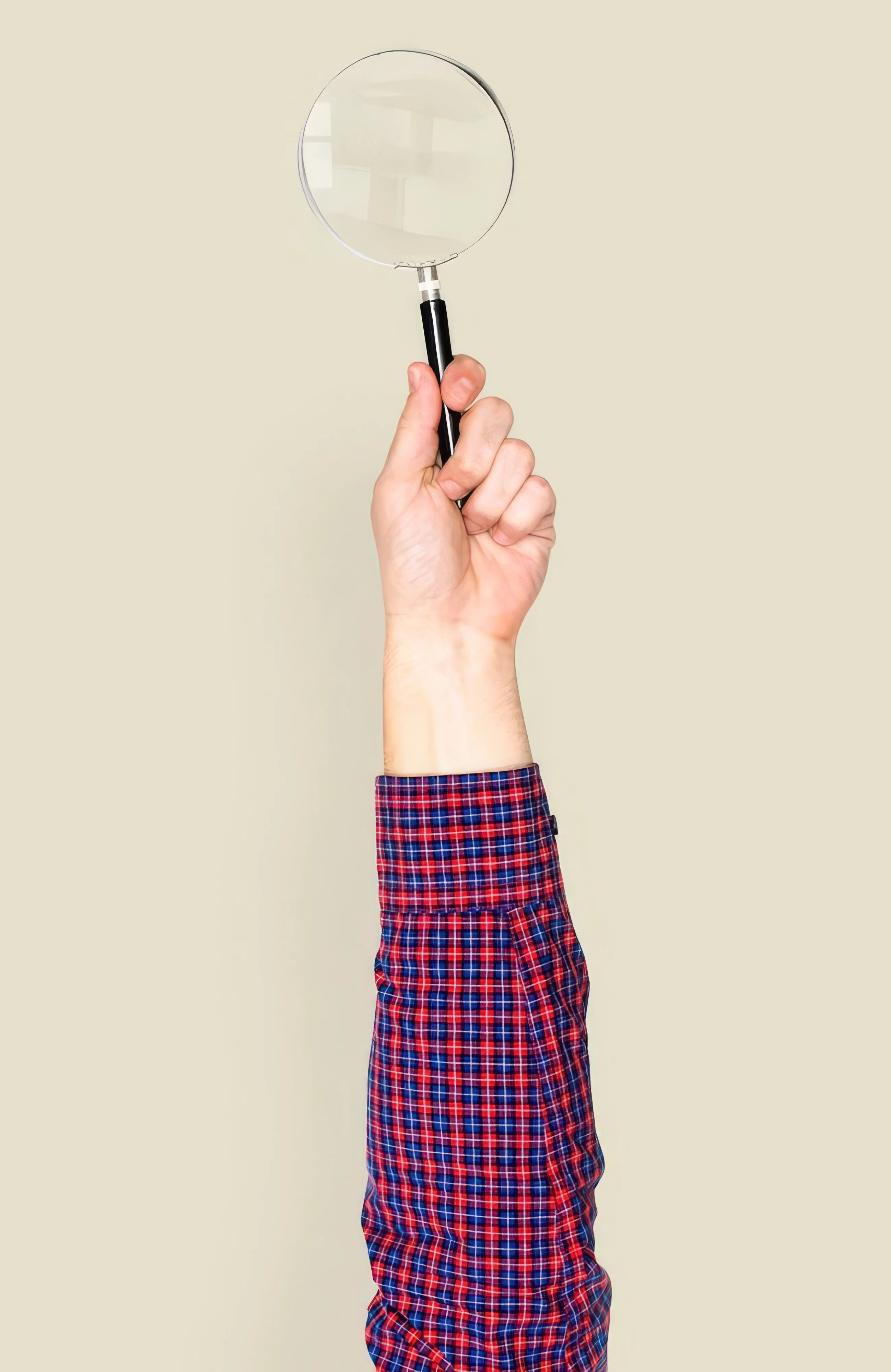 A hand holding up a magnifying glass.