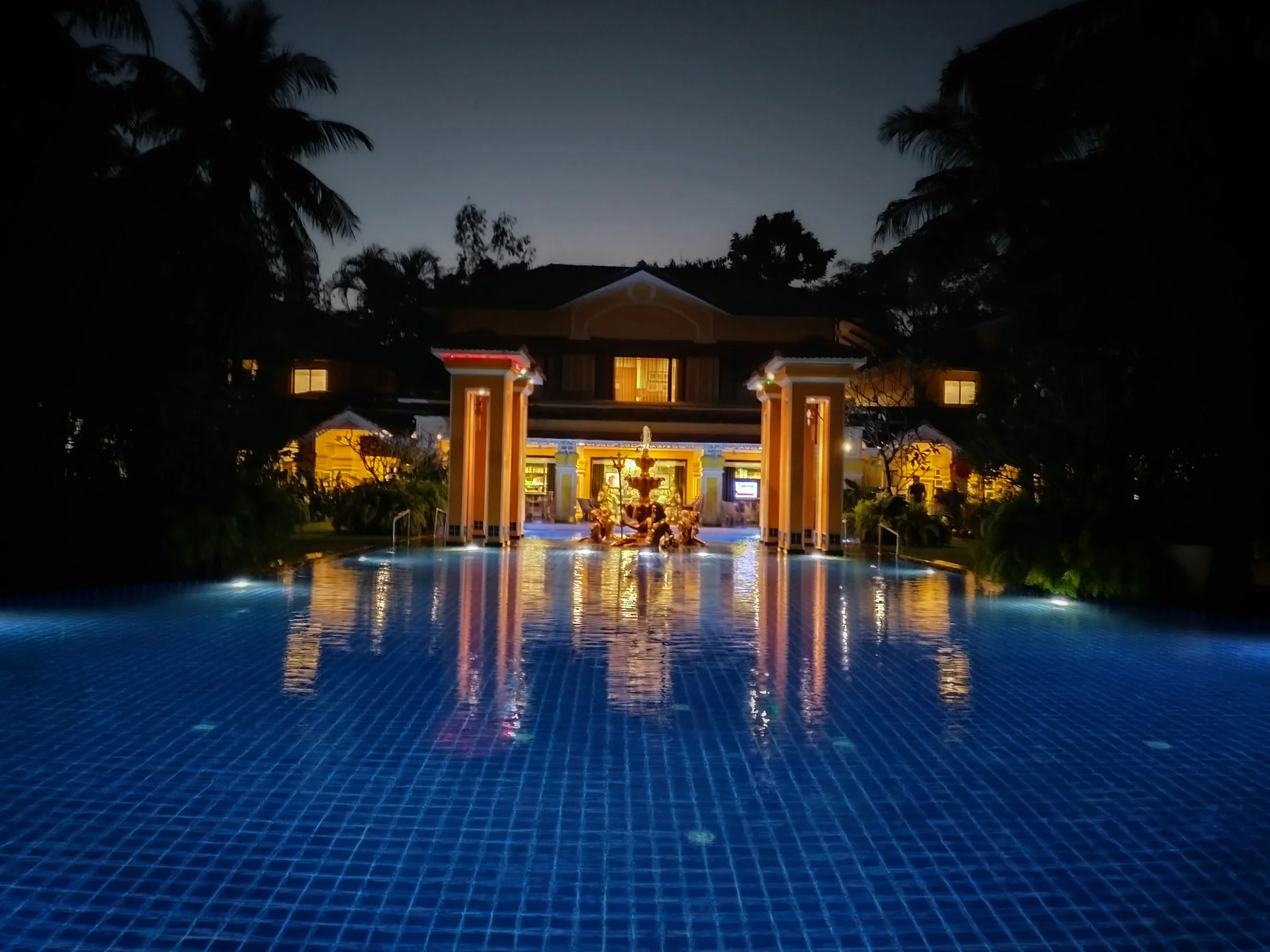 A villa lit at night, reflected in its pool.