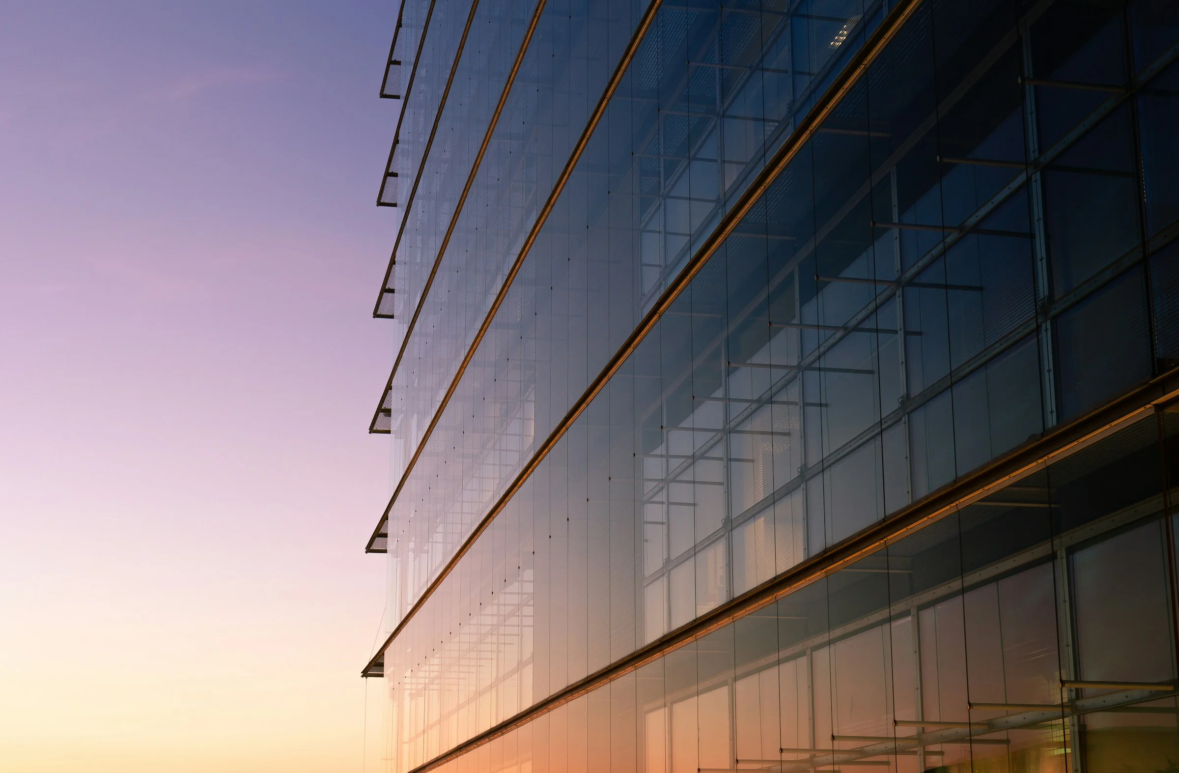 A glass building facade at dusk.